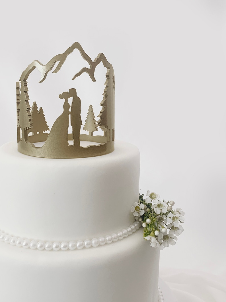 Acrylic Laser Cut Cake Topper. Round Mountain Design with wedding couple silhouette. Painted in bright gold on top of simple white cake. Custom Engrave and personalization.