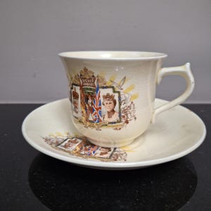 May include: A vintage teacup and saucer set with a commemorative design for the Silver Jubilee of King George V and Queen Mary in 1935. The set features images of the royal couple and the text "Silver Jubilee" and "Their Majesties 1935".