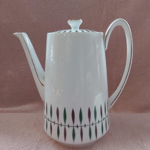 May include: White ceramic coffee pot with a gold trim and a geometric design in shades of green and brown.