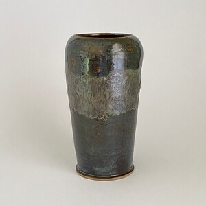 May include: A dark green ceramic vase with a brown glaze and a light green band around the middle. The vase has a rounded bottom and a slightly flared top.