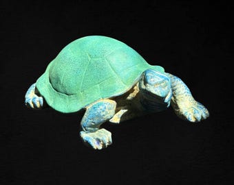 May include: A green and blue ceramic turtle sculpture. The turtle is in a walking position with its head turned to the side.