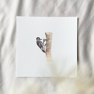 May include: A watercolor painting of a small brown and black bird perched on a tree trunk. The bird is facing to the right and has a long, pointed beak. The tree trunk is light brown and has a rough texture.