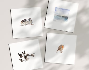 May include: Four watercolor paintings on white cardstock. The first painting shows three sparrows perched on a branch. The second painting shows a seascape with two birds flying overhead. The third painting shows a flock of geese flying in formation. The fourth painting shows a robin perched on a branch.