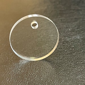 以下が含まれることがあります： 中央に小さな穴が開いた透明な円形の アクリル ディスクです。