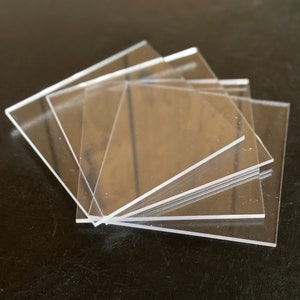 May include: A stack of four clear acrylic squares.