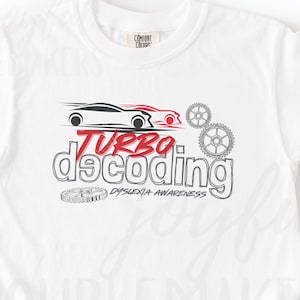 Puede incluir: Camiseta blanca con un gráfico rojo y negro que dice "Turbo Decoding Dyslexia Awareness". Se combina con pantalones deportivos grises y zapatos sin cordones a cuadros blancos y negros.