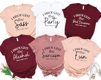 May include: Six t-shirts with different sayings on them. The shirts are in various colors, including pink, white, and maroon. The sayings on the shirts are "I brought the sass", "I brought the party", "I brought the bad decisions", "I brought the alcohol", "I brought the sarcasm", and "I brought the fun".