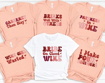May include: Six pink and white t-shirts with wine-themed text and graphics. The shirts feature phrases like "Cabernet Then Slay", "Drinks Well With Others", "Partners in Wine", "Wine Girl Wasted", "Bride on Cloud Wine", and "I Make Pour Decisions".