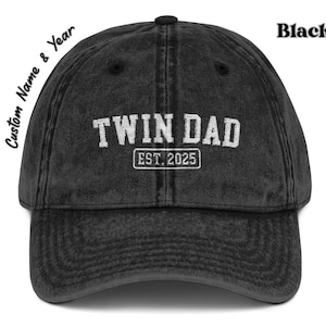 May include: Black distressed baseball cap with white embroidered text "Twin Dad Est. 2025".