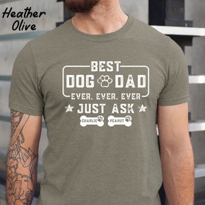 May include: Heather olive t-shirt with the text "BEST DOG DAD EVER. EVER. EVER. JUST ASK" in white. The shirt also features a paw print and the names "Charlie" and "Peanut" below the text.
