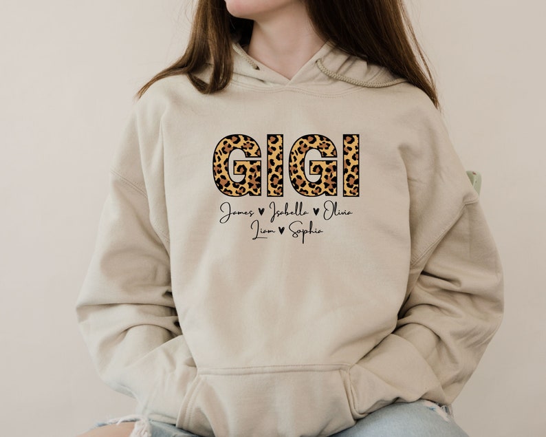 May include: A beige hoodie with a leopard print "GIGI" design and the names "James, Isabella, Olivia, Liam, Sophie" written below in black.