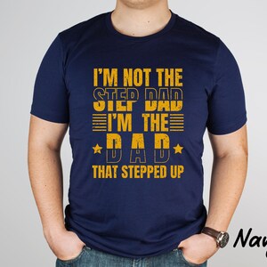 Puede incluir: Camiseta azul marino con un gr&aacute;fico amarillo que dice "No soy el padrastro, soy el padre que dio un paso adelante".