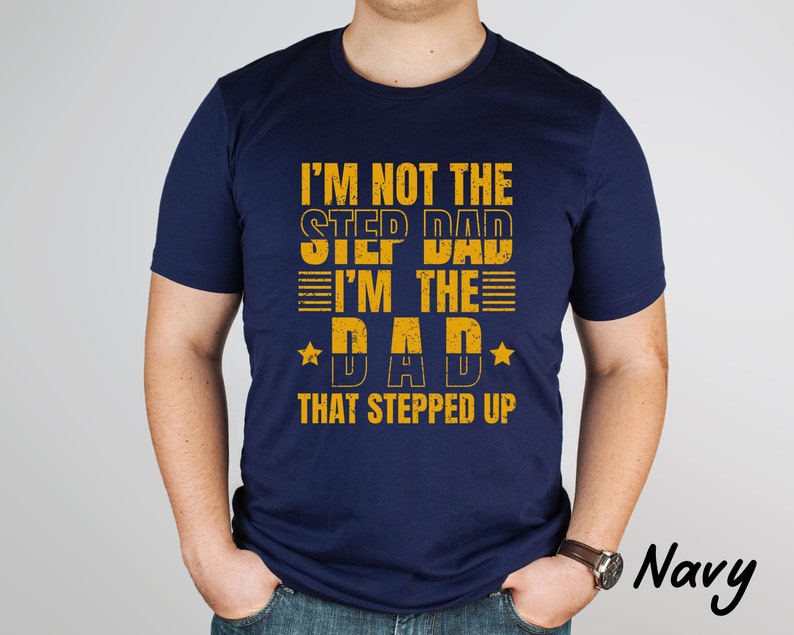 Puede incluir: Camiseta azul marino con un gr&aacute;fico amarillo que dice "No soy el padrastro, soy el padre que dio un paso adelante".