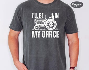 Könnte beinhalten: Ein dunkelgraues T-Shirt mit einer weißen Grafik eines Traktors und dem Text "I'll be in my office".