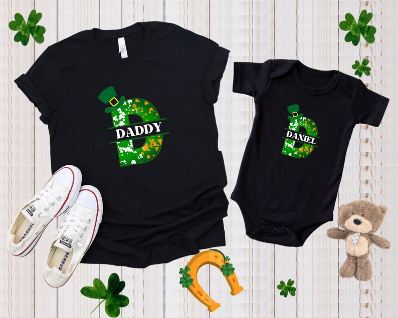 Puede incluir: Camiseta y body negros con un dise&ntilde;o de tr&eacute;bol verde y sombrero de duende. La camiseta dice "Daddy" y el body dice "Daniel".
