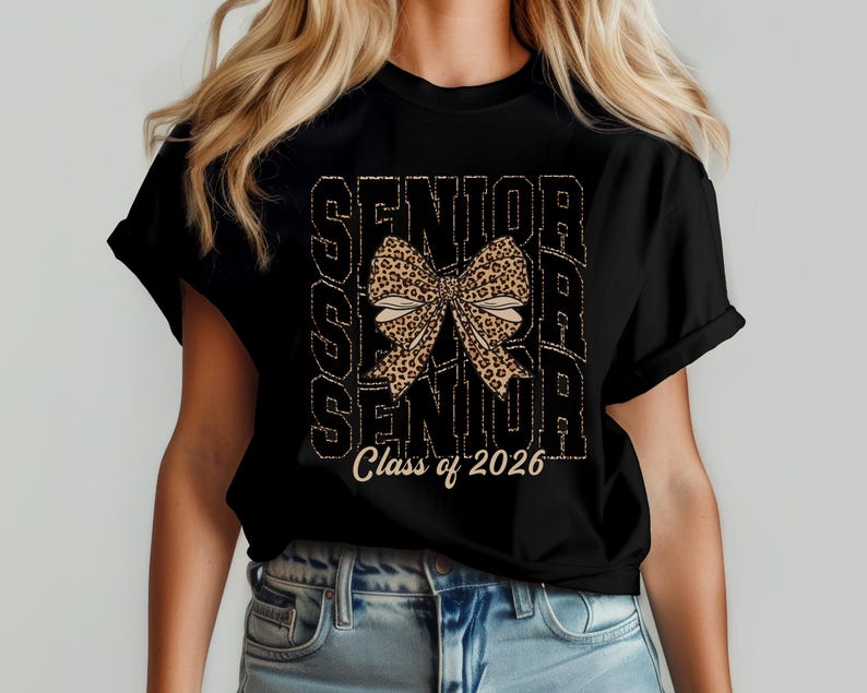 Puede incluir: Camiseta negra con un gr&aacute;fico de la palabra "Senior" repetida tres veces con un lazo de estampado de leopardo en el centro. El texto "Class of 2026" est&aacute; impreso debajo del gr&aacute;fico.