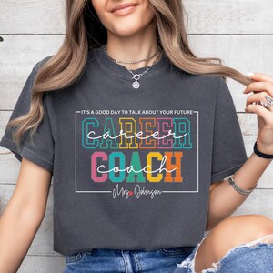 May include: A dark grey t-shirt with the text "It's a good day to talk about your future: Career Coach - Mrs. Johnson" in colourful letters.