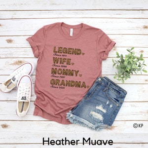 May include: A heather mauve t-shirt with the text "LEGEND. Since 1971 WIFE. Since 1996 MOMMY. Since 1997 GRANDMA. Since 2021" printed in black with a leopard print design.