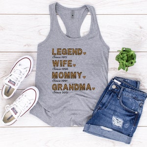 May include: Gray tank top with a leopard print design that says "LEGEND Since 1971", "WIFE Since 1996", "MOMMY Since 1997", and "GRANDMA Since 2021".