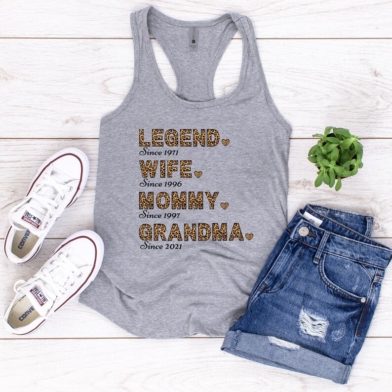 May include: Gray tank top with a leopard print design that says "LEGEND Since 1971", "WIFE Since 1996", "MOMMY Since 1997", and "GRANDMA Since 2021".