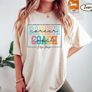 May include: Ivory t-shirt with a colourful graphic that says "IT'S A GOOD DAY TO TALK ABOUT YOUR FUTURE - career coach - Mrs. Johnson - "
