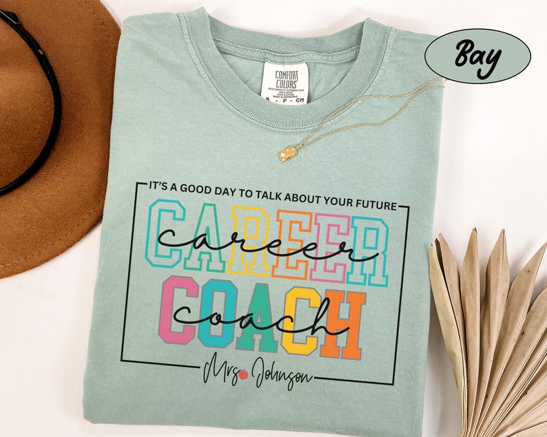 May include: A light blue t-shirt with the text "It's a good day to talk about your future" above the words "career coach" in colourful block letters. The text "Mrs. Johnson" is below the words "career coach".