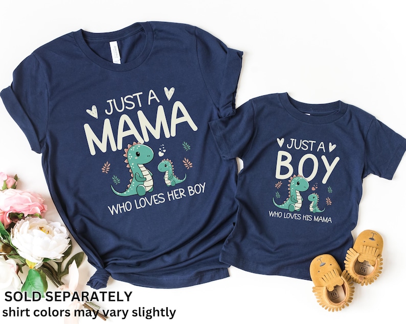 May include: Two navy blue t-shirts with a dinosaur graphic and text that reads "Just a Mama who loves her boy" and "Just a Boy who loves his mama".