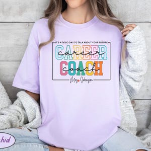 May include: A lavender t-shirt with the text "It's a good day to talk about your future - Career Coach - Mrs. Johnson" in colourful block letters.