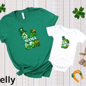Puede incluir: Camiseta verde y blanca con la palabra "MAMA" y un dise&ntilde;o de tr&eacute;bol. Body blanco con la letra "D" y el nombre "DANIEL" en un dise&ntilde;o de tr&eacute;bol.