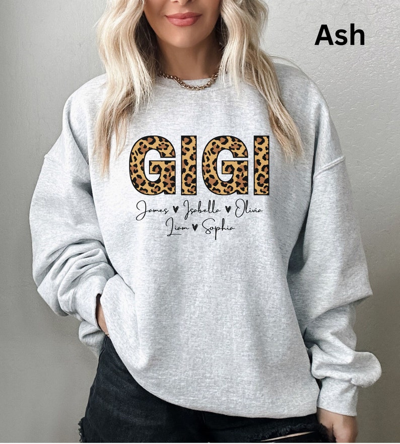 May include: Grey sweatshirt with the word "GIGI" in large, leopard print letters. Below the word are the names "James, Isabella, Olivia, Liam, Sophie" with hearts between each name.