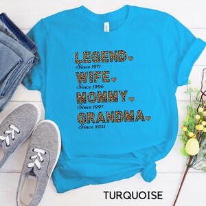 May include: Turquoise blue t-shirt with a leopard print design and the text "LEGEND Since 1971 WIFE Since 1996 MOMMY Since 1997 GRANDMA Since 2021" with a heart after each line.