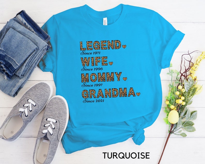 May include: Turquoise blue t-shirt with a leopard print design and the text "LEGEND Since 1971 WIFE Since 1996 MOMMY Since 1997 GRANDMA Since 2021" with a heart after each line.