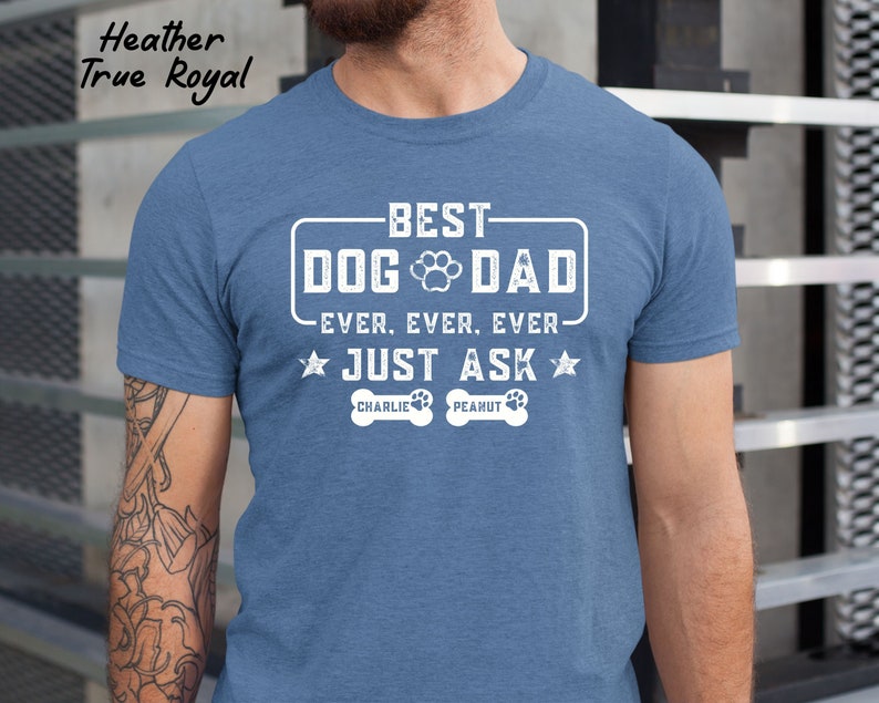 May include: Heather True Royal blue t-shirt with the text "BEST DOG DAD EVER. EVER. EVER. JUST ASK" in white. The shirt includes paw prints and the names "Charlie" and "Peanut" below the text.