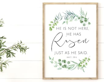 May include: A framed print with a watercolor illustration of green leaves and branches surrounding the text "HE IS NOT HERE, HE HAS RISEN JUST AS HE SAID. MATT. 28:6".