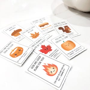 Op de afbeelding: Een verzameling kleine, witte kaarten met kleurrijke illustraties en tekst. De kaarten bevatten afbeeldingen van een pompoen, eikel, esdoornblad en andere herfstthema's. Elke kaart heeft een unieke boodschap.