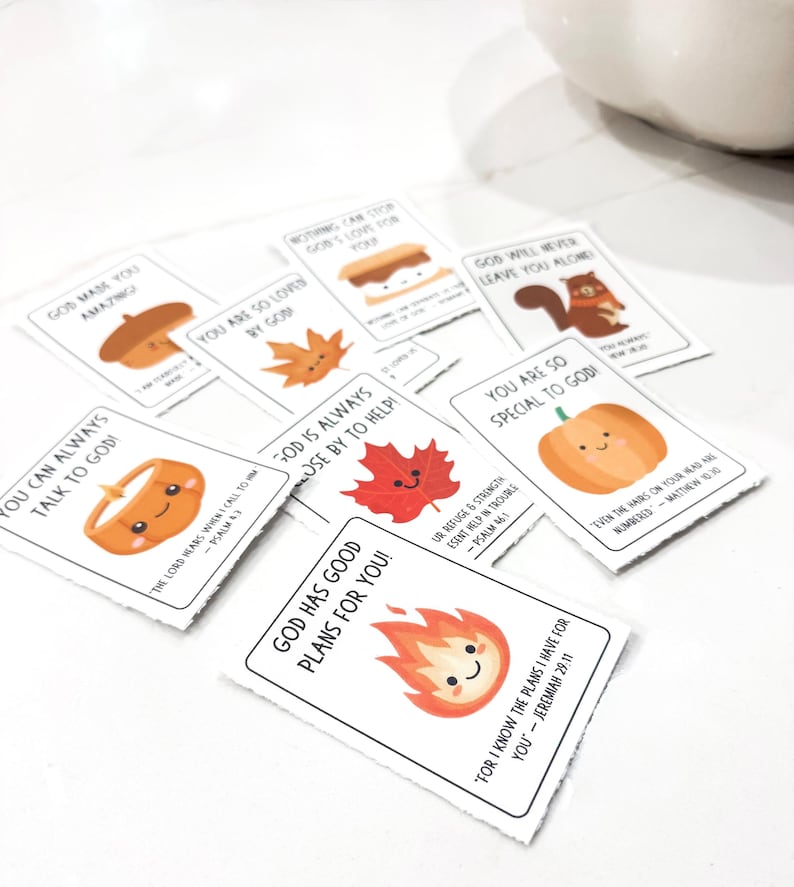 Op de afbeelding: Een verzameling kleine, witte kaarten met kleurrijke illustraties en tekst. De kaarten bevatten afbeeldingen van een pompoen, eikel, esdoornblad en andere herfstthema's. Elke kaart heeft een unieke boodschap.