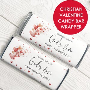 Op de afbeelding: Twee witte candybarwikkels met rode en perzik hartafbeeldingen. De wrappers hebben de tekst "all wrapped up in God's love" en "Happy Valentine's Day". Een rode cirkel leest "Christian Valentine Candy Bar Wrapper".