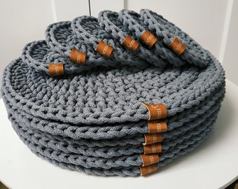 May include: A stack of gray crocheted coasters with brown leather labels that say "semi".