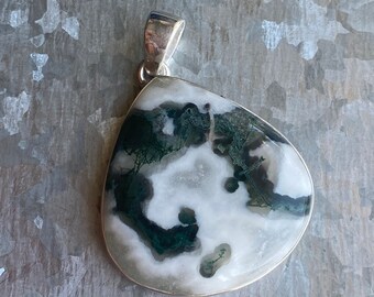 May include: A silver pendant featuring a green and white moss agate stone. The stone has a unique, swirling pattern.