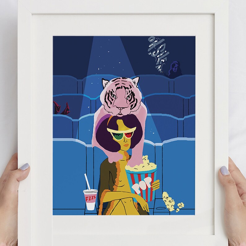 May include: A framed art print featuring a woman in 3D glasses holding popcorn and a drink at a movie theater. A pink tiger is perched on her shoulders. The artwork has a retro, pop art style with a blue and yellow color scheme.