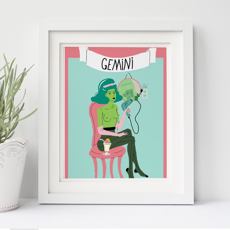 May include: Framed art print with a Gemini zodiac illustration. A green-skinned figure sits on a pink chair, holding a hairdryer. The background is light blue with a pink border. The word "GEMINI" is displayed on a banner above the figure.