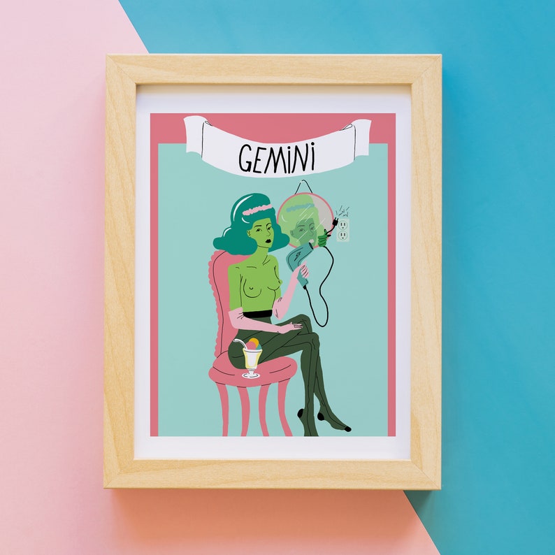 May include: A framed art print with a retro illustration of the Gemini zodiac sign. The artwork shows a green-skinned figure seated in a pink chair, holding a hair dryer. The word "GEMINI" is displayed on a banner above the figure.