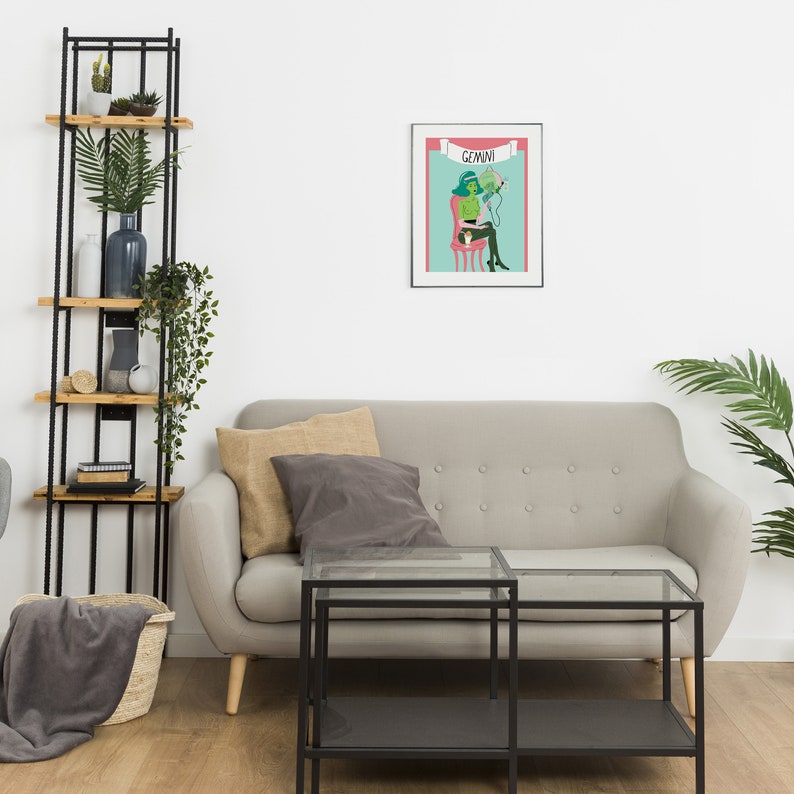 May include: A framed art print displaying a Gemini zodiac illustration. The artwork shows a green and black figure seated on a pink chair, with the word "Gemini" above. The print is positioned above a grey sofa. The room also features a black metal shelving unit.