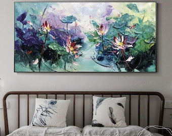 May include: Abstract painting of pink and white lotus flowers in a pond with green lily pads. The painting is done in a textured style with visible brushstrokes. The painting is framed and hanging on a wall above a bed with pillows.