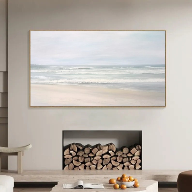May include: A framed painting of a seascape with white waves crashing on a sandy beach. The sky is a light blue and the water is a light gray. The painting is in a minimalist style.