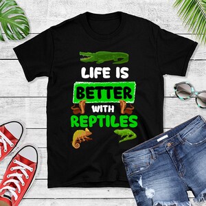 May include: Black t-shirt with a green graphic that says "Life is Better with Reptiles". The graphic also includes images of a crocodile, a chameleon, and a snake.