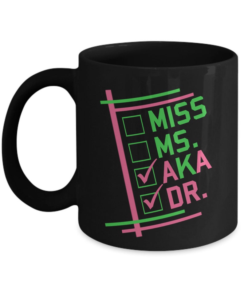 Puede incluir: Taza de cer&aacute;mica negra con asa blanca que presenta el texto "MISS MS. AKA DR." en verde y rosa. El dise&ntilde;o incluye casillas de verificaci&oacute;n y l&iacute;neas en los mismos colores. Una taza de caf&eacute; elegante y funcional.