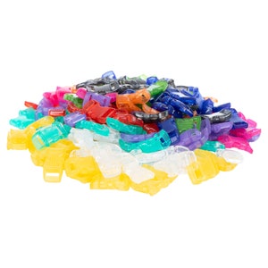 May include: A pile of colorful plastic buckles in various shades of blue, green, red, yellow, orange, and purple. The buckles are small and have a simple design.