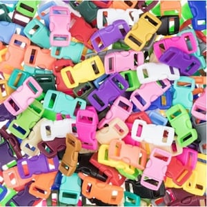 Op de afbeelding: Een verzameling kleurrijke plastic zijgespsluitingen in verschillende tinten, waaronder roze, paars, geel, groen en oranje. De gespen zijn verspreid en tonen hun vergrendelingsmechanisme. Geschikt voor knutselprojecten.