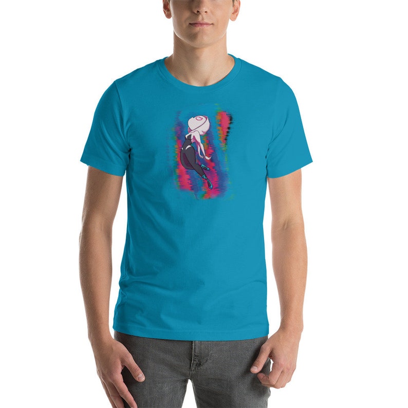 May include: A turquoise blue t-shirt with a graphic of a female superhero in a black and white suit with pink and blue accents. The superhero is in a dynamic pose with her arms outstretched.